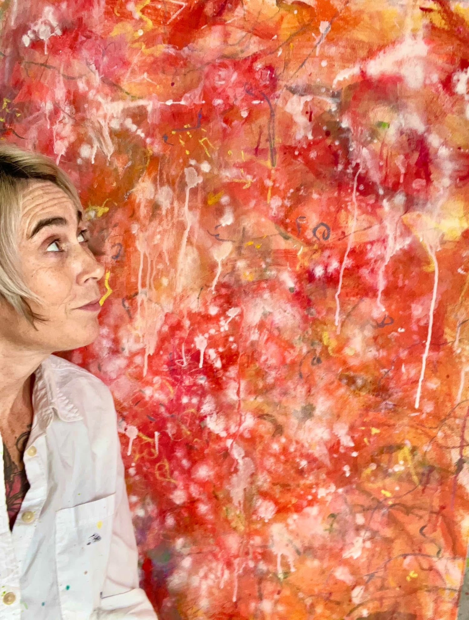 Michelle Ramos standing in front of her vibrant Bright Spring abstract paintings in her studio, featuring bold reds, oranges, and colorful drips