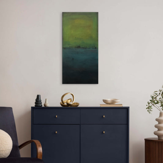 Framed horizontal earth‑tone abstract painting hanging above neutral furniture, showing soft transitions of clay, ochre, teal, and green.