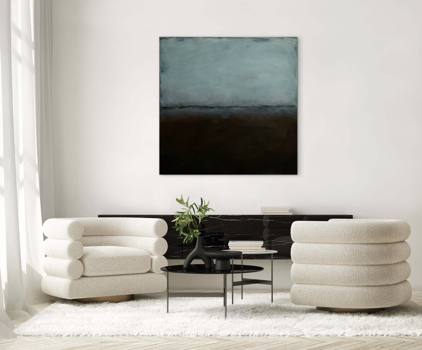 Artist sitting on the studio floor in front of a large abstract painting with blue and dark tones.
