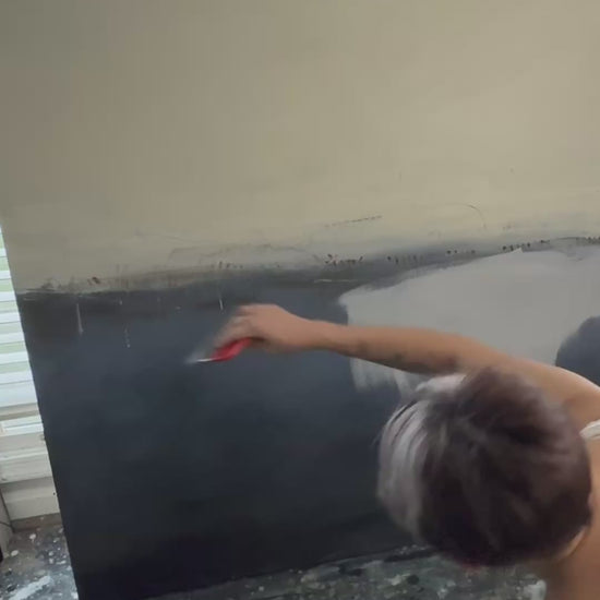 Artist painting a large abstract canvas in muted neutral tones, showing brushwork and layering during the creation process.